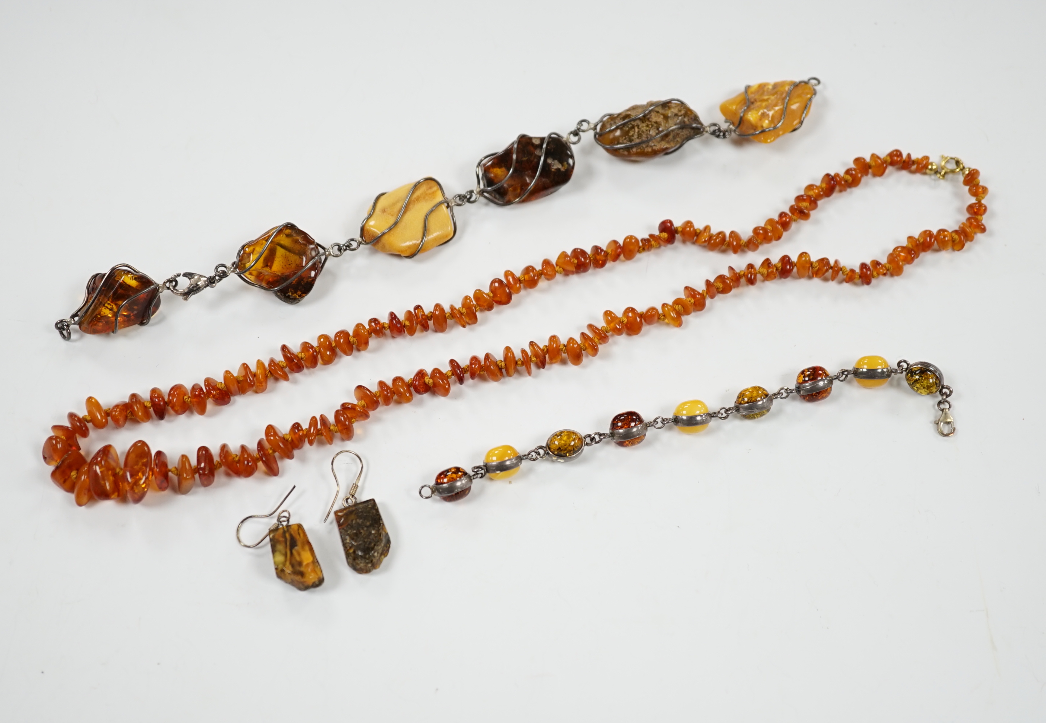 Two white metal and Baltic amber pebble set bracelets, one stamped 925, largest 25cm, a pair of similar drop earrings and an amber necklace.